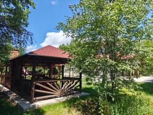 a wooden gazebo in a park with a tree at Gyulak Guesthouse in Izvoare