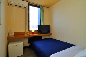 a bedroom with a bed and a desk with a television at Ribera Inn in Satsumasendai