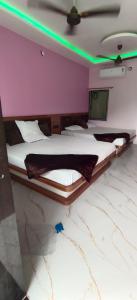a bedroom with two beds in a room with green lights at Shri Goara palece in Godarpura