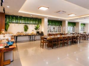 a restaurant with wooden tables and chairs and green curtains at M&M Hotel in Vang Vieng