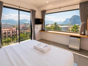 a bedroom with a bed and large windows at M&M Hotel in Vang Vieng