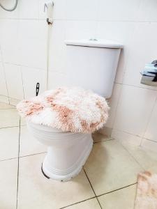 a bathroom with a white toilet with a rug on it at AWESOME HOME's in Arusha +9 photos