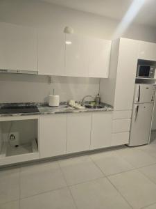a white kitchen with white cabinets and a refrigerator at Beach 2 Min - Bright Central Studio - AC in Santa Maria