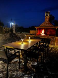 a wooden table with chairs and a fireplace at night at Agiokampos Resort in Agiokampos
