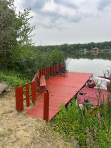 a wooden dock with benches next to a body of water at Dunasor1 Apartman in Dömsöd +6 photos