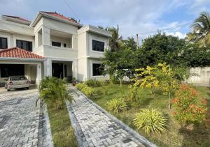 a large white house with a garden in front of it at Palm Breeze Villa in Mannar