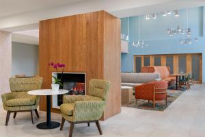 a lobby with a fireplace and chairs and a table at Hampton Inn & Suites Rockland in Thomaston
