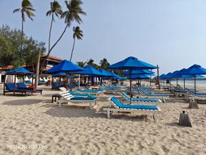 a beach with blue umbrellas and chairs on the sand at Backpackers inn Hostel in Trincomalee +25 photos