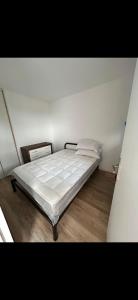 a bedroom with a bed with white sheets and wooden floors at Appartement Ipanema Sud in Canet-en-Roussillon