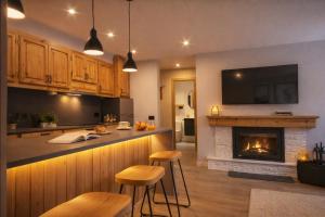 a kitchen with a fireplace and two bar stools at Luderna - Apartamento con terraza Artigues in Arties
