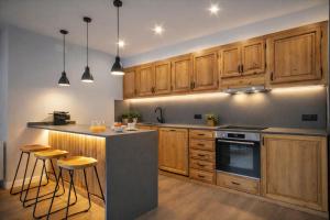 a kitchen with wooden cabinets and a island with bar stools at Luderna - Apartamento con terraza Artigues in Arties +4 photos