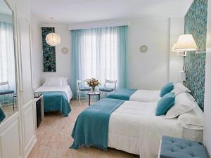 a hotel room with two beds and a table at Hotel Playa del Carmen in Barbate