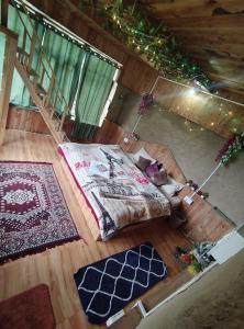 a room with a bed and two rugs on the floor at Offbeat Trails in Jibhi