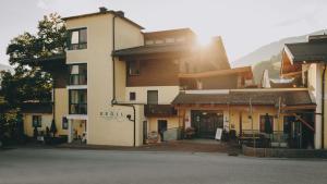 a building with the sun shining behind it at Hotel Gasthof Kröll, 1x Großglockner kostenlos, Kinder bis 12 Jahre frei, Restaurant mit regionaler Küche in Niedernsill