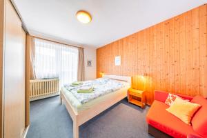 a bedroom with a bed and a red couch at Pension Kubát in Špindlerův Mlýn