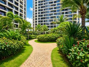 a walkway through a park with palm trees and buildings at Pinnacle Moments Residence in Phnom Penh