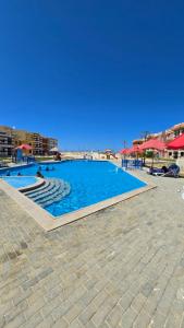 a swimming pool with blue water in a resort at Porto Matrouh Elabd Family in Marsa Matruh