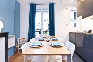 パリにあるBright and Newly Renovated Apartment, Hip Canal Saint-Martin Area, Central Parisのキッチン(木製テーブル、椅子付)、ダイニングルーム