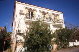 a white building with balconies and trees in front of it at Ulrika in Aegina Town