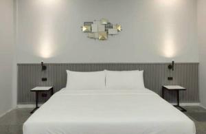 a bedroom with a white bed with two tables at ปราสาทรีสอร์ท in Prasat