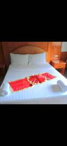 a white bed with a red dress on it at ปราสาทรีสอร์ท in Prasat