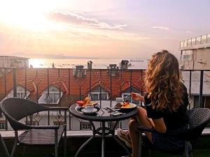 a woman sitting at a table eating food on a balcony at Angel's Home Suites - Angel Group Hotels in Istanbul