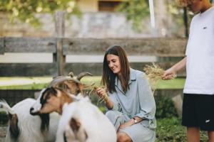 a woman is feeding some hay to two goats at Hotel Gasthof Kröll, 1x Großglockner kostenlos, Kinder bis 12 Jahre frei, Restaurant mit regionaler Küche in Niedernsill +47 photos