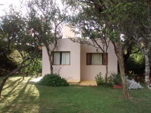 una casa blanca con árboles delante en Cabañas Entre Verde, en Los Hornillos