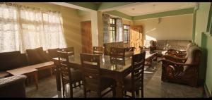 a dining room with chairs and a table and a couch at Tilanjali Stay in Soreng