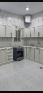 an empty kitchen with white cabinets and a stove at Highland Residence Al namas in Lahbey