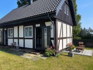 a small black and white cottage with a door at Zagroda Nadmorska Brzezina in Jastrzębia Góra