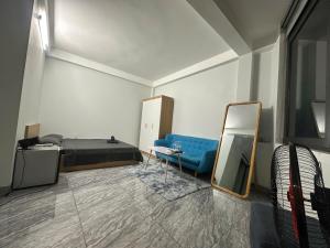 a room with a bed and a blue couch and a mirror at Mayhome in Long Biên