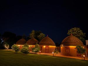 a row of four huts with lights at night at Urban Dhani in Gurgaon +14 photos