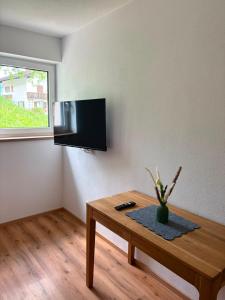 a living room with a table and a tv on the wall at FEWO-TomKO in Fügenberg