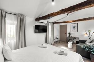 a white bedroom with a bed and a living room at Konoba Most Rooms in Buzet