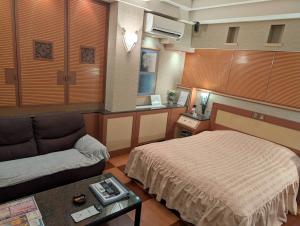 a bedroom with a bed and a couch and a table at Hotel Shuyukan (Adult Only) in Izumi-Sano