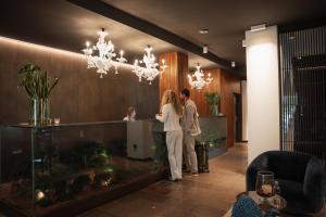 two people standing at a counter in a lobby at ELGUS Nature Retreat in Brentonico +70 photos