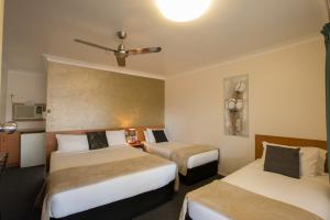a hotel room with two beds and a ceiling at David Motor Inn in Rockhampton
