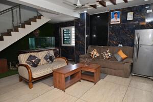a living room with a couch and a table and a refrigerator at Hotel Ganesh Mahalakshmi Inn in Guntūr