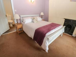 a bedroom with a large white bed and a fireplace at Ewe Cottage in Ripon