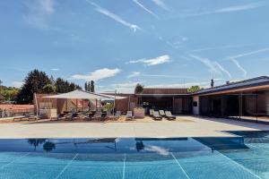 a swimming pool next to a house with chairs and a building at Landhotel Wratschko - Wirtshaus - Gamlitz - ehem Hotel am Marktplatz in Gamlitz