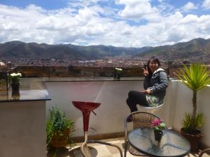 a woman sitting on the ledge of a balcony talking on a cell phone at Hostal Casa Del Inka in Cusco