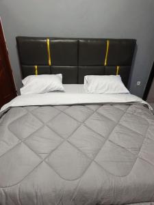 a large bed with a black headboard and white pillows at Mtg Apartment in Rubavu
