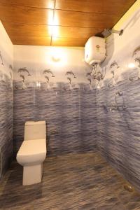 a bathroom with a toilet and birds on the wall at लेक एंड वुड्स in Bhīm Tāl