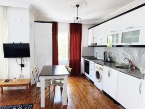 a kitchen with white cabinets and a table and a dining room at KAŞ MERKEZ İMREN APART 2 in Kaş +1 photo