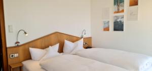 two beds with white pillows in a bedroom at Gästehaus Seeblick in Langenargen