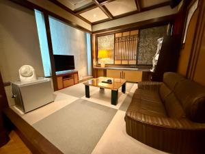 a living room with a couch and a coffee table at Hotel Shuyukan (Adult Only) in Izumi-Sano