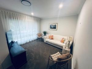 a living room with a white couch and a window at Guest house Que Sera in Cooranbong