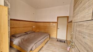 a bedroom with a bed in a wooden room at Daisy Divine in Harsil