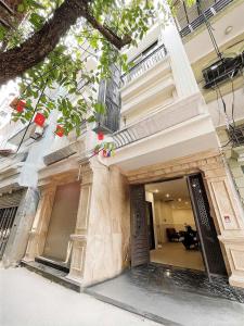 a white building with a door and a tree at Harmony apartment in Noi Bai